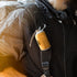 Person wearing a dark coat with a yellow sleeping bag attached to their backpack